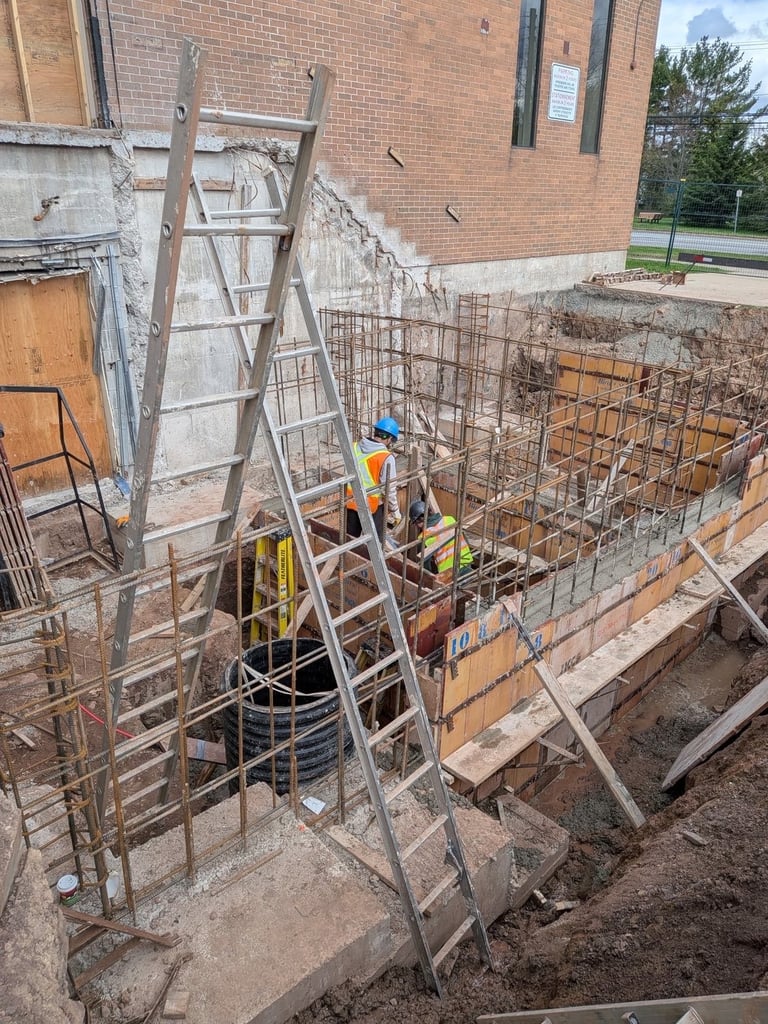 Construction worker in safety vest at brick building site with metal scaffolding, ladder, and rebar framework